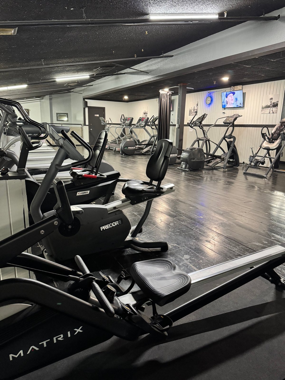 Modern gym interior with Matrix exercise bikes and cardio equipment on dark flooring, well-lit with tv screens